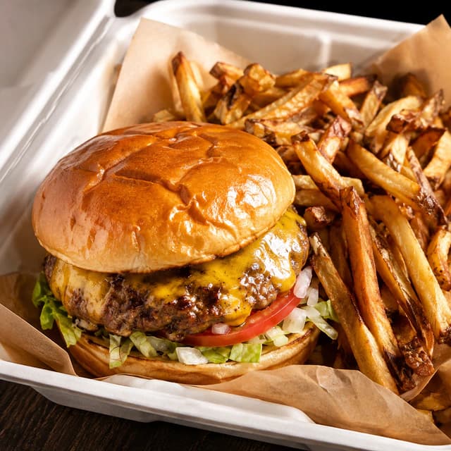 Enhanced takeout cheeseburger and fries with warm studio lighting